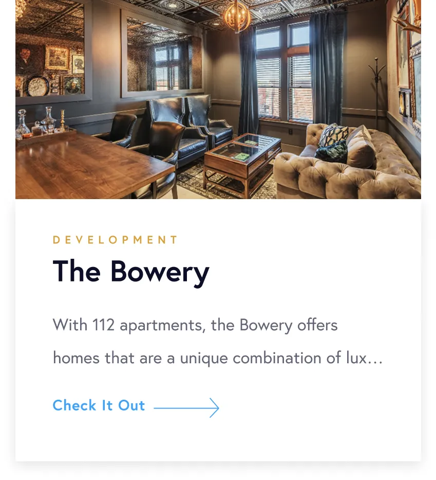 Stylish living room with tufted sofa, leather armchairs, wooden table, and large windows with dark curtains.