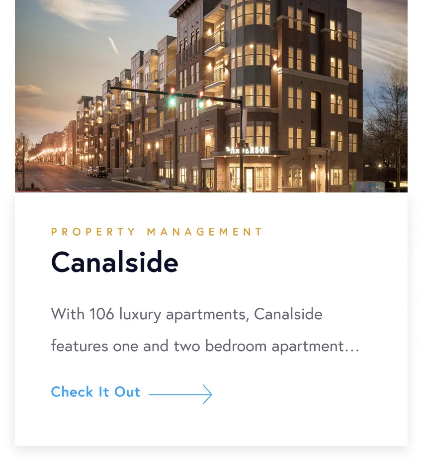 Evening view of The Anderson luxury apartment building at Canalside with lights on and street visible.