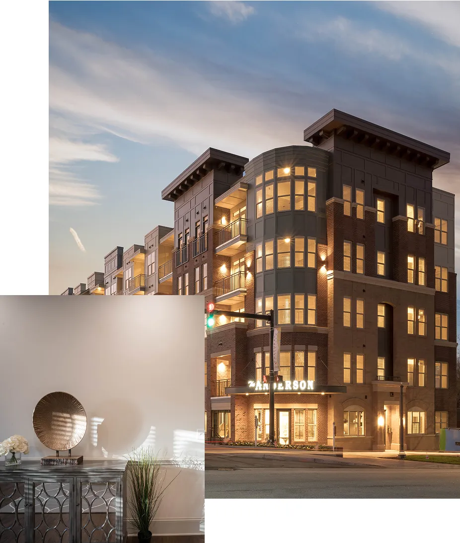 Modern four-story apartment building with lit windows at dusk and a decorative interior side table with plants and a round sculpture.