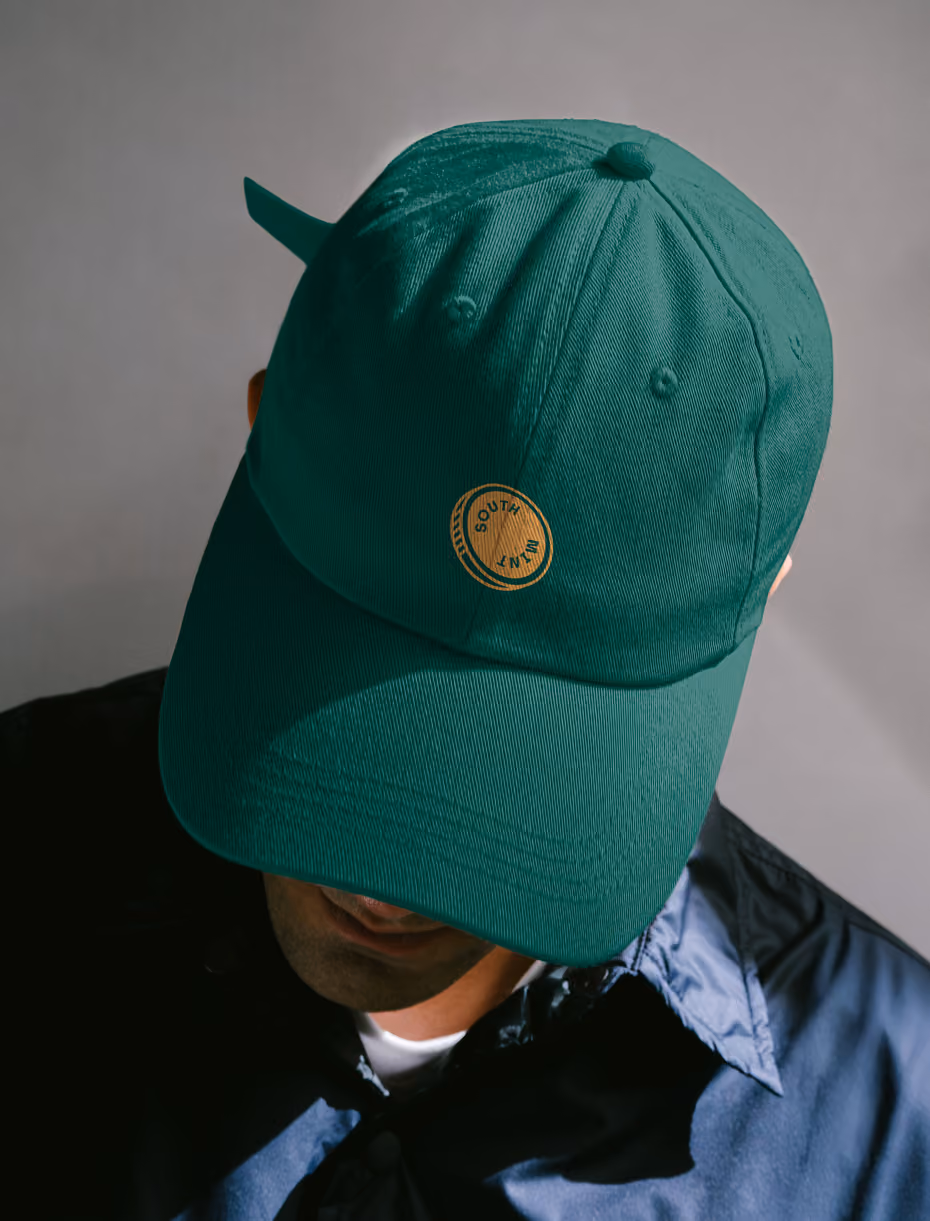 A man wearing a dark green branded South Mint hat
