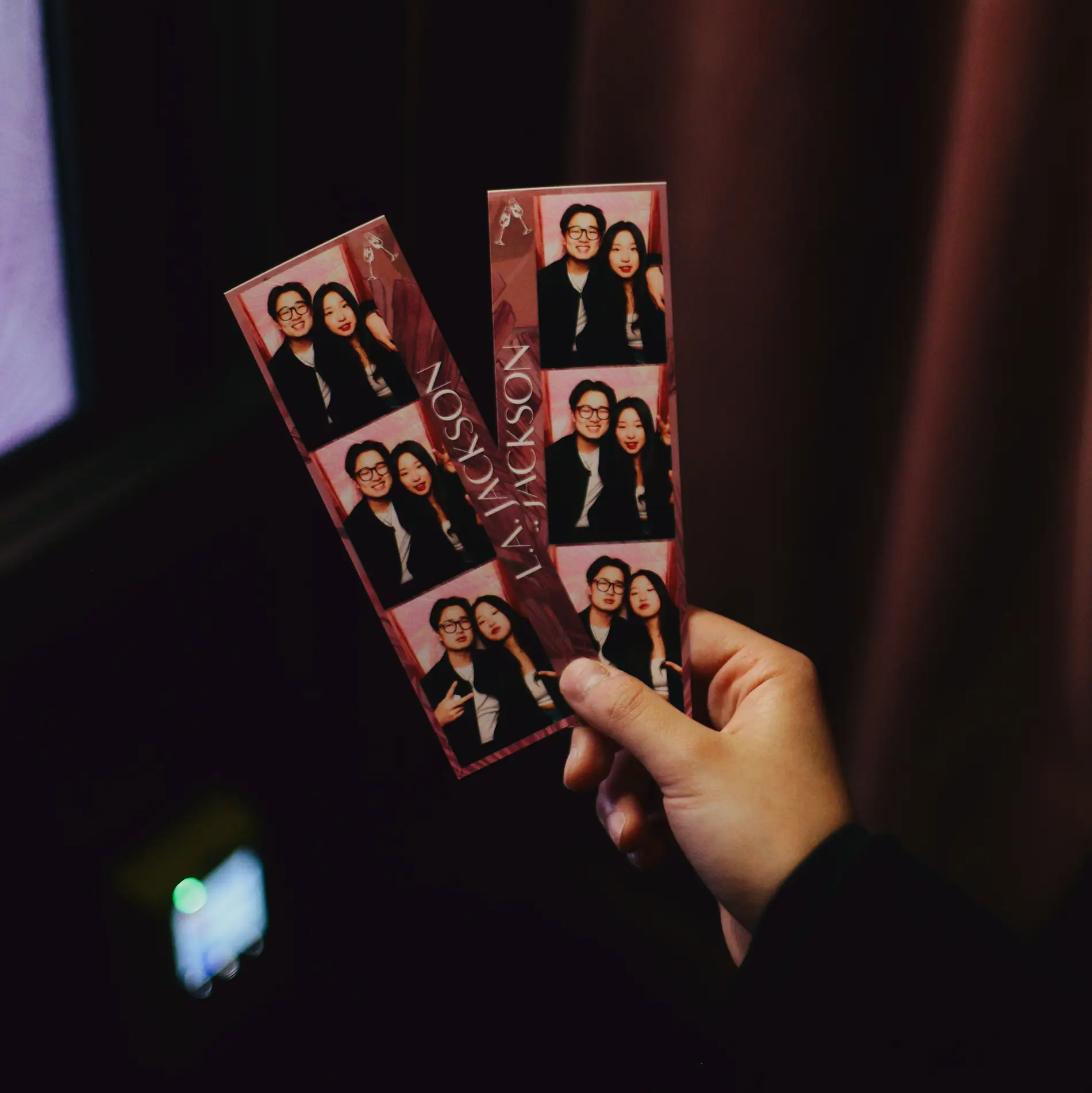 Person holding branded photo booth strips