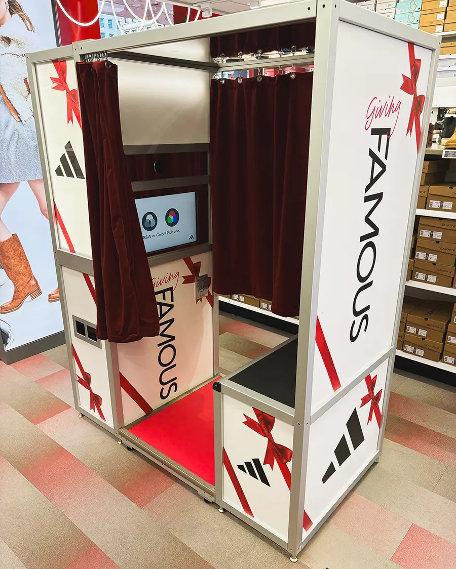 Fully wrapped Adidas x Famous Footwear photo booth with red ribbon and gift bow graphics inside a retail store