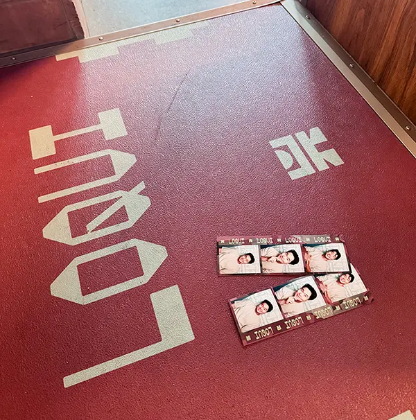 Custom LOQUI branded floor graphic inside the Majestic Photobooth at Runway Playa Vista, with a printed photostrip resting on top