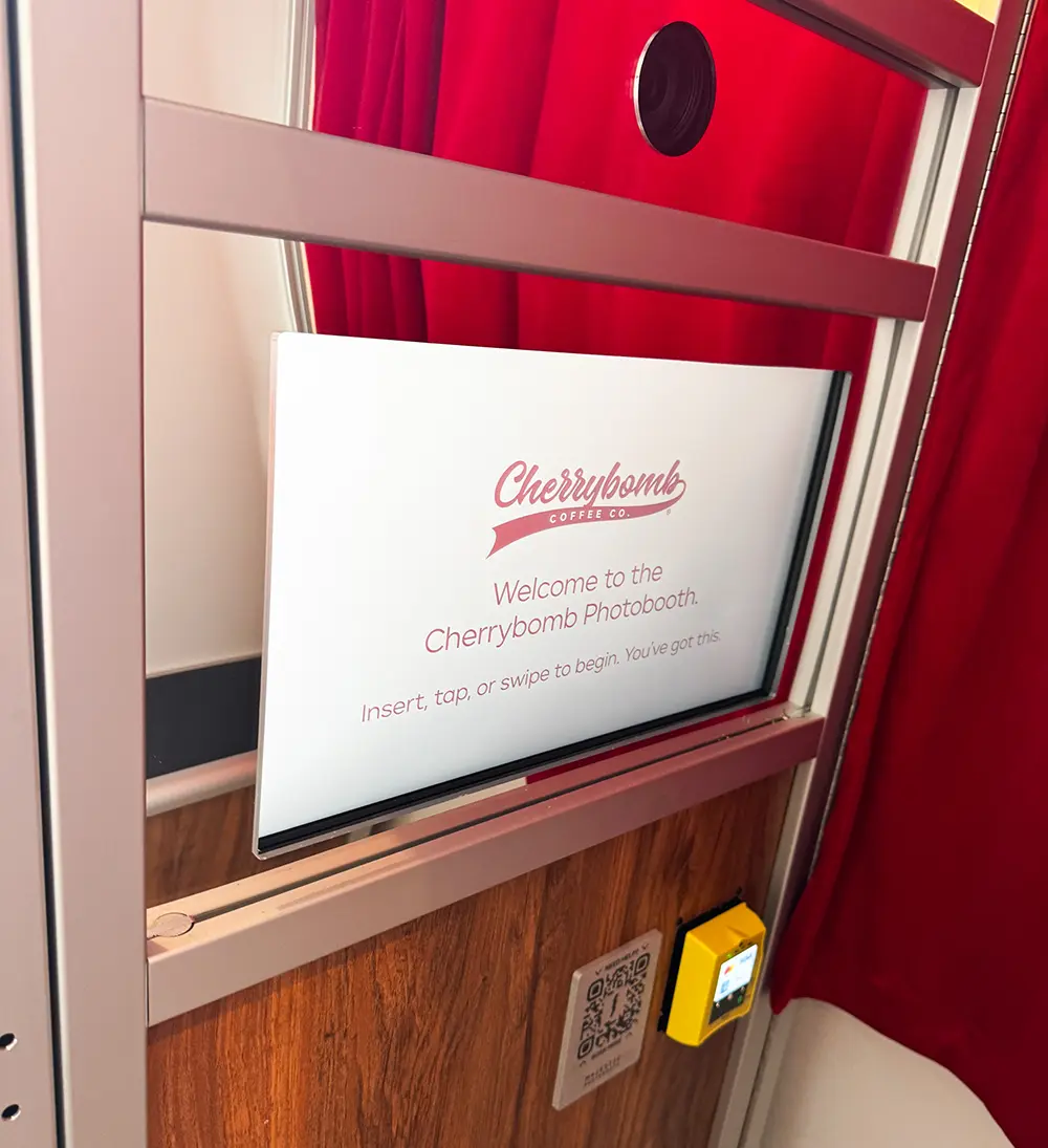 Cherrybomb Coffee Co. branded welcome screen inside the Majestic photo booth, with tap to pay reader and red velvet curtain
