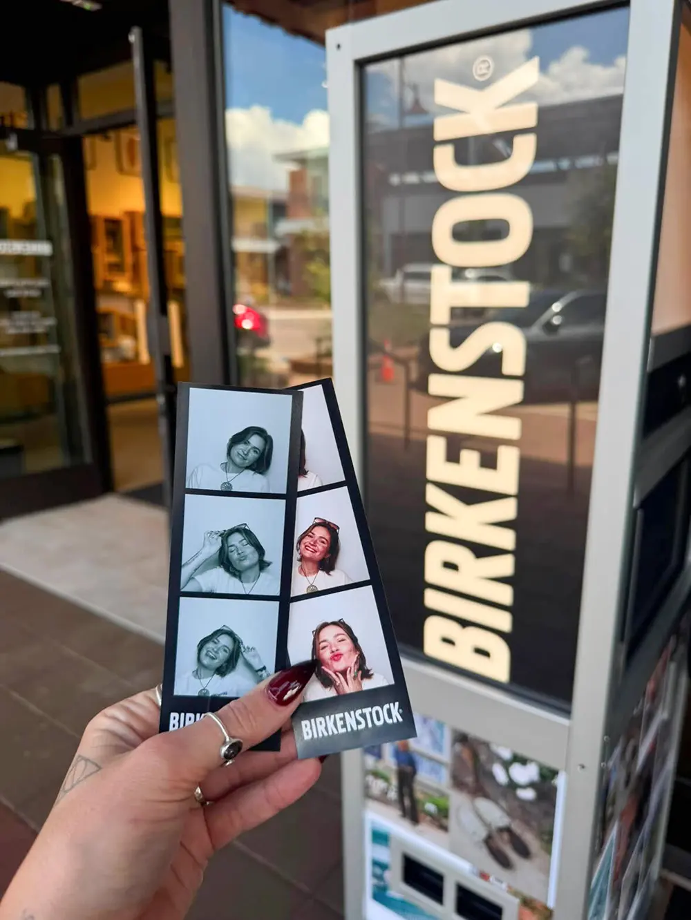 Two Birkenstock branded photo strips, one black and white and one colour, held up outside the Birkenstock store in Boulder, Colorado