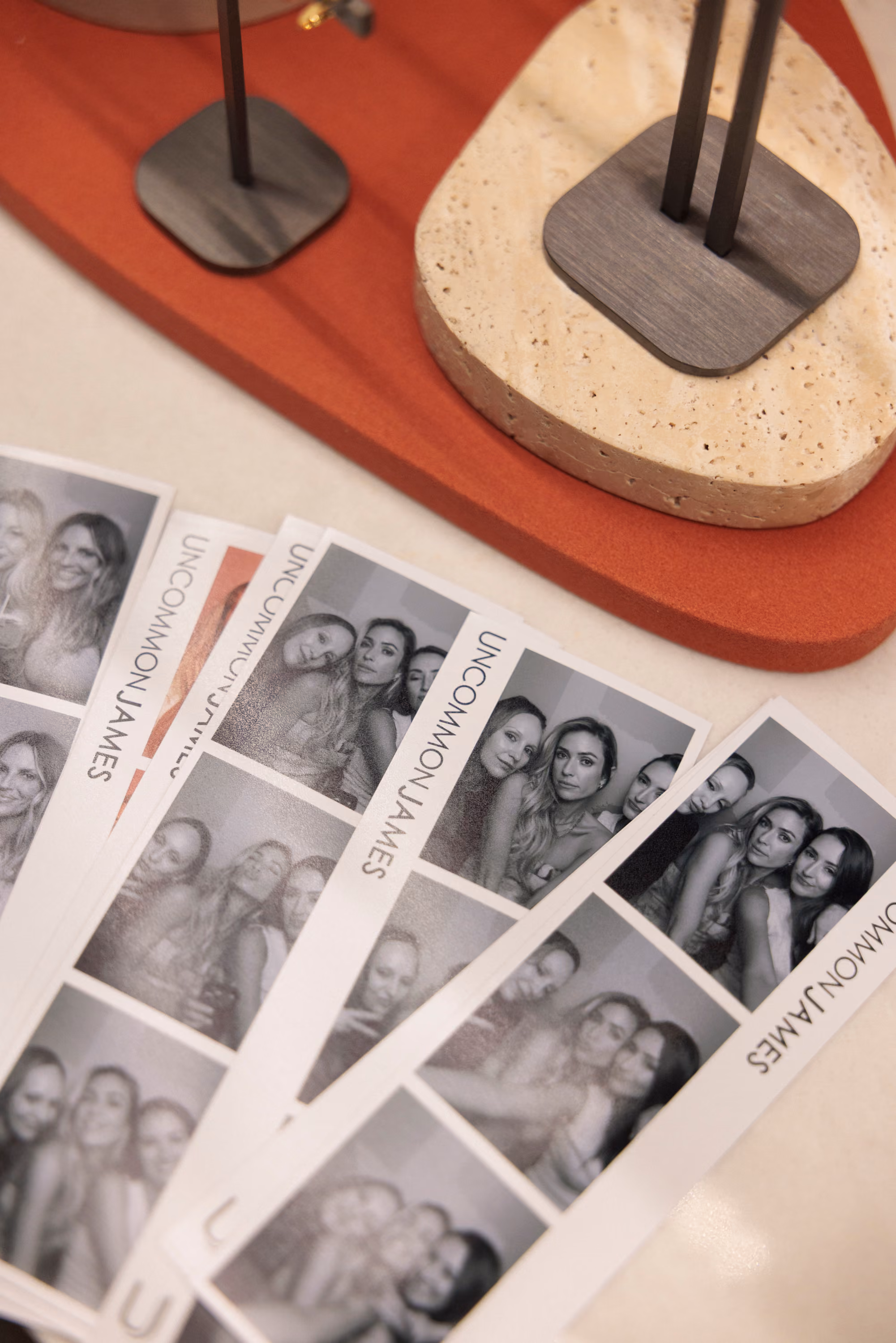 Black and white Uncommon James photo strips fanned out on the store counter beside travertine and terracotta jewelry displays