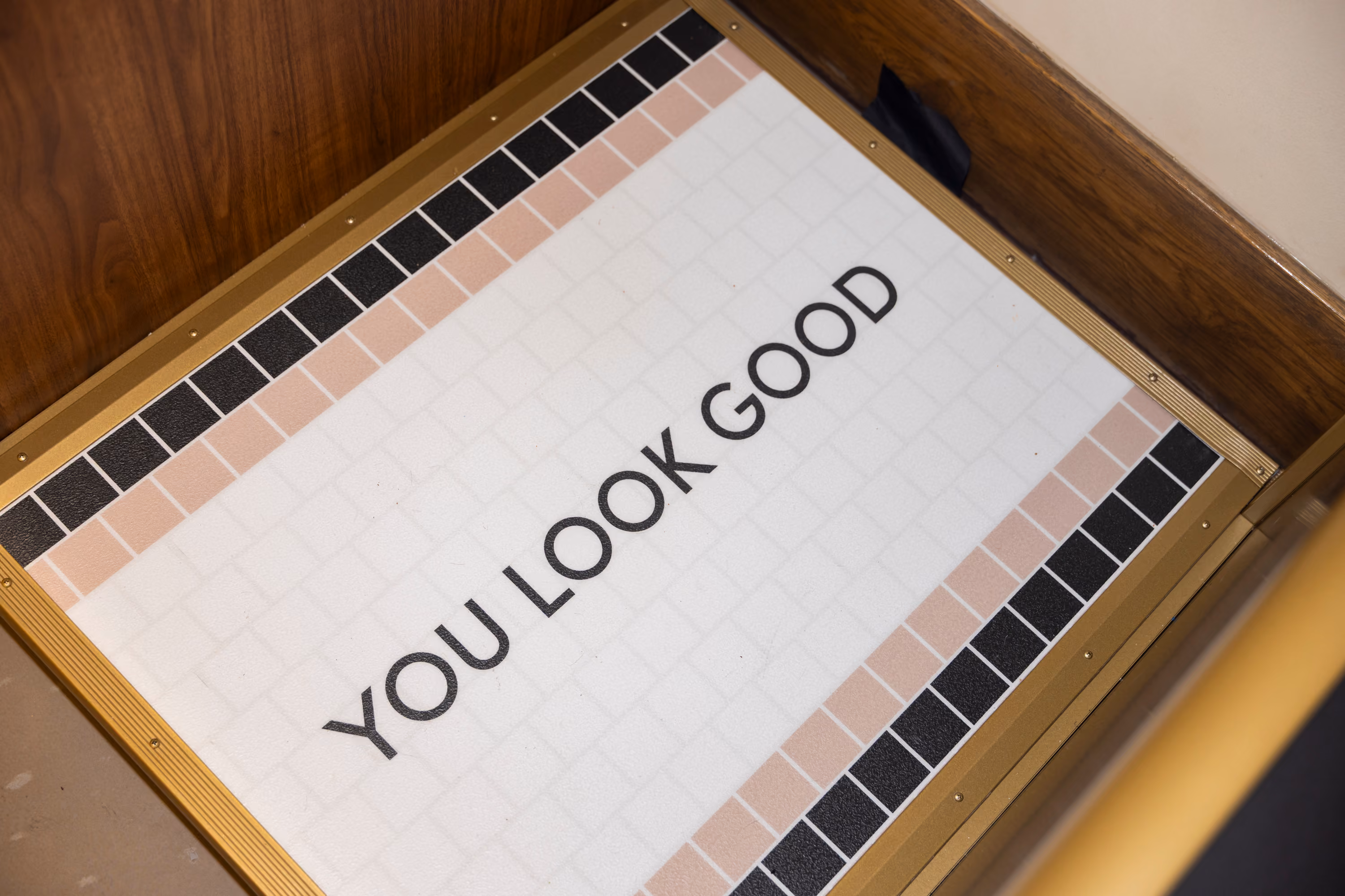 Printed tile floor inside the Uncommon James photo booth reading YOU LOOK GOOD in black on white with blush and black tile borders