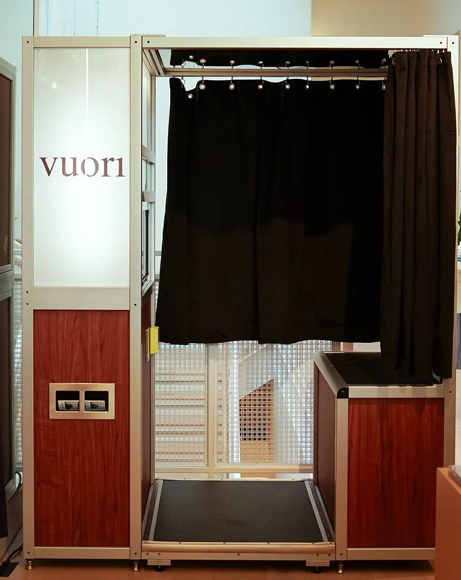 photo booth with a backlit vuori panel, walnut lower panels and a black velvet curtain installed inside the Vuori store in Chicago