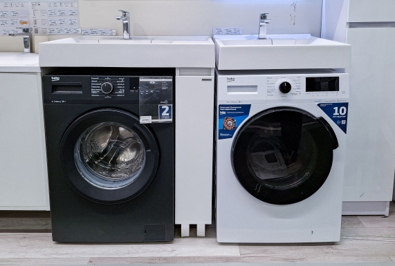 Integrated washing machine fitted within modern kitchen cabinetry with the cupboard door open