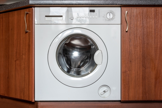 Built-in washing machine installed within fitted kitchen units showing integrated appliance design