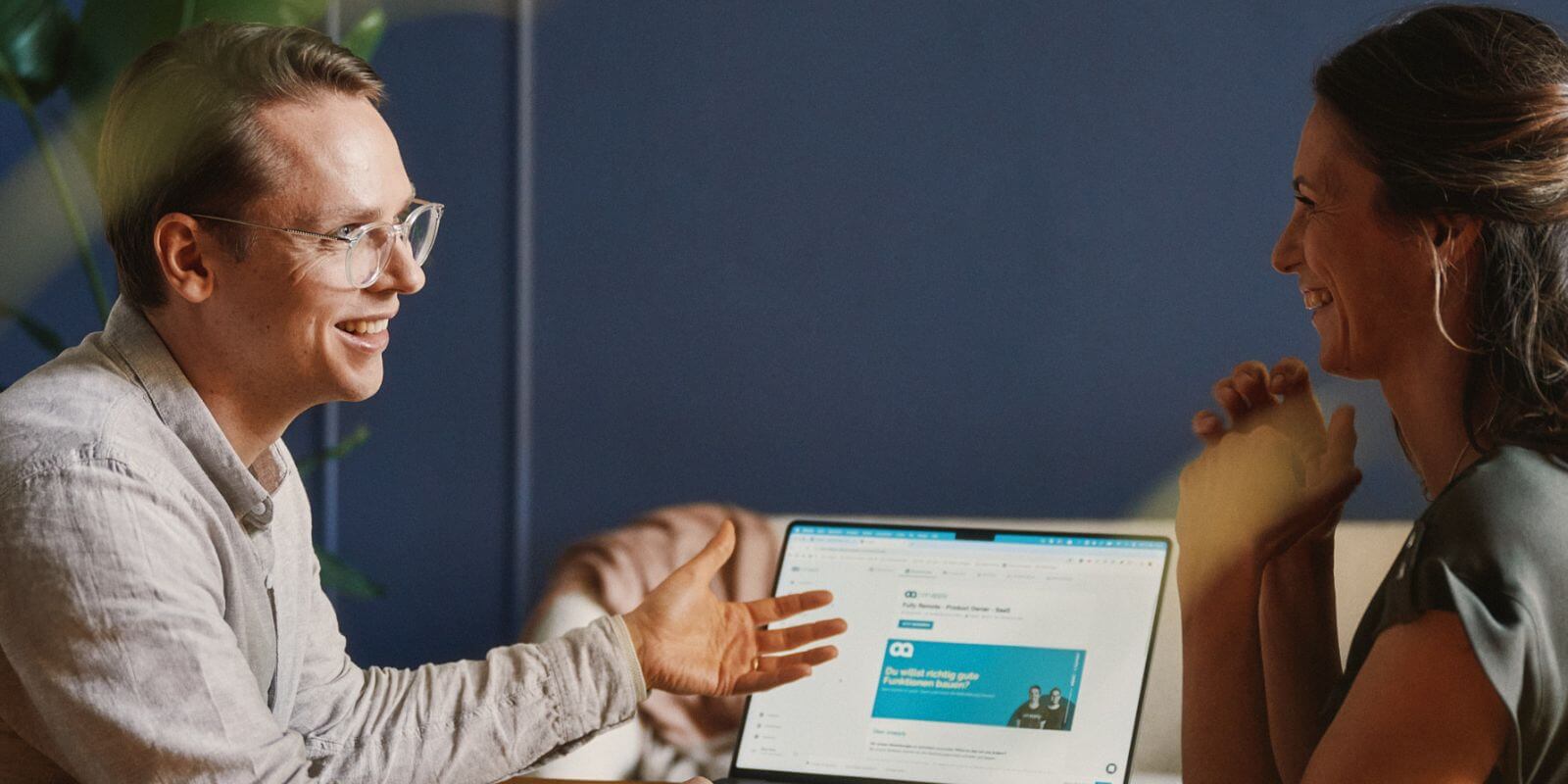 Mann spricht mit Frau vor einem Laptop - positives Gespräch
