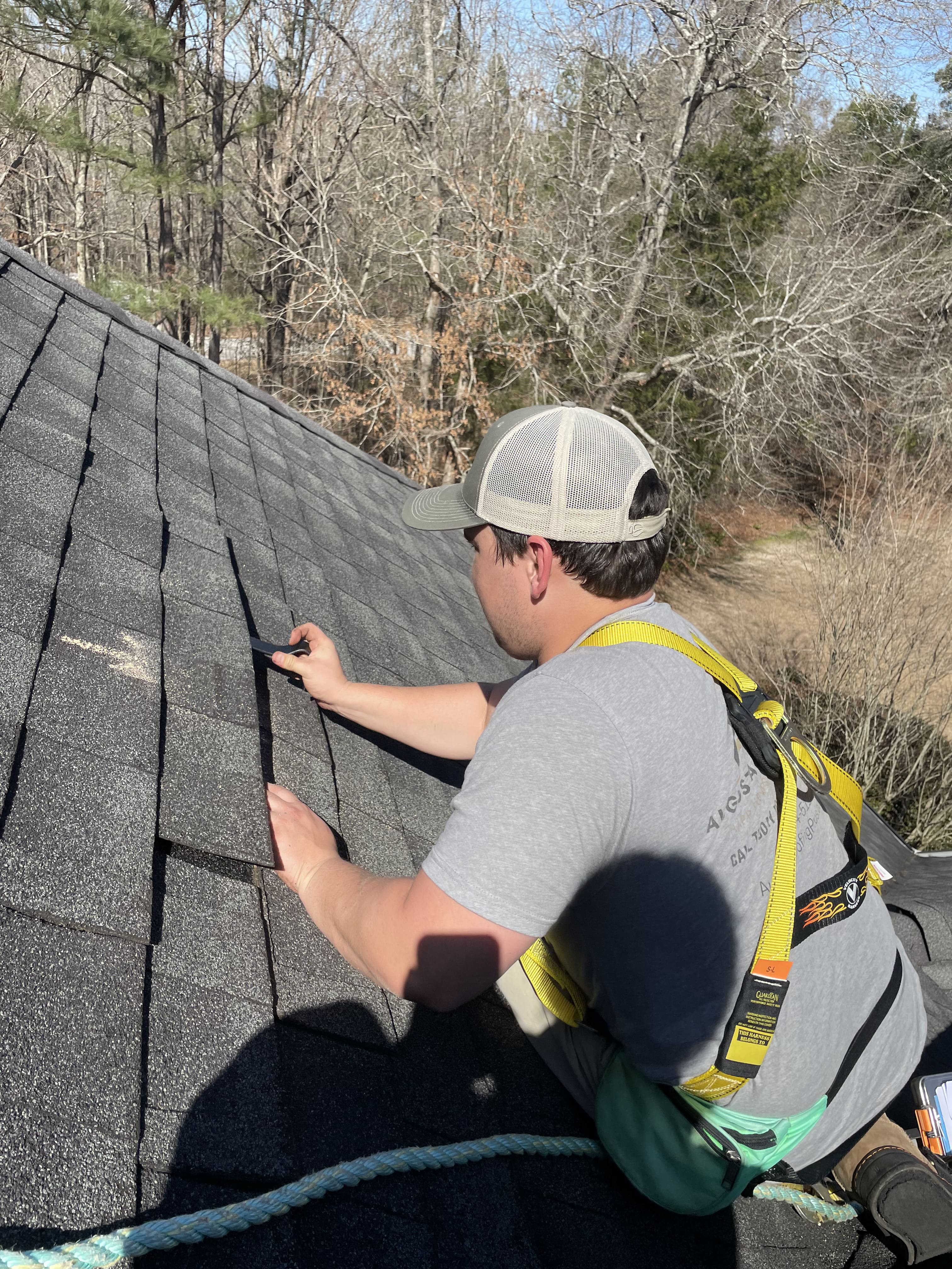 Professional roofer wearing Cougar Paws installing asphalt shingles on residential roof
