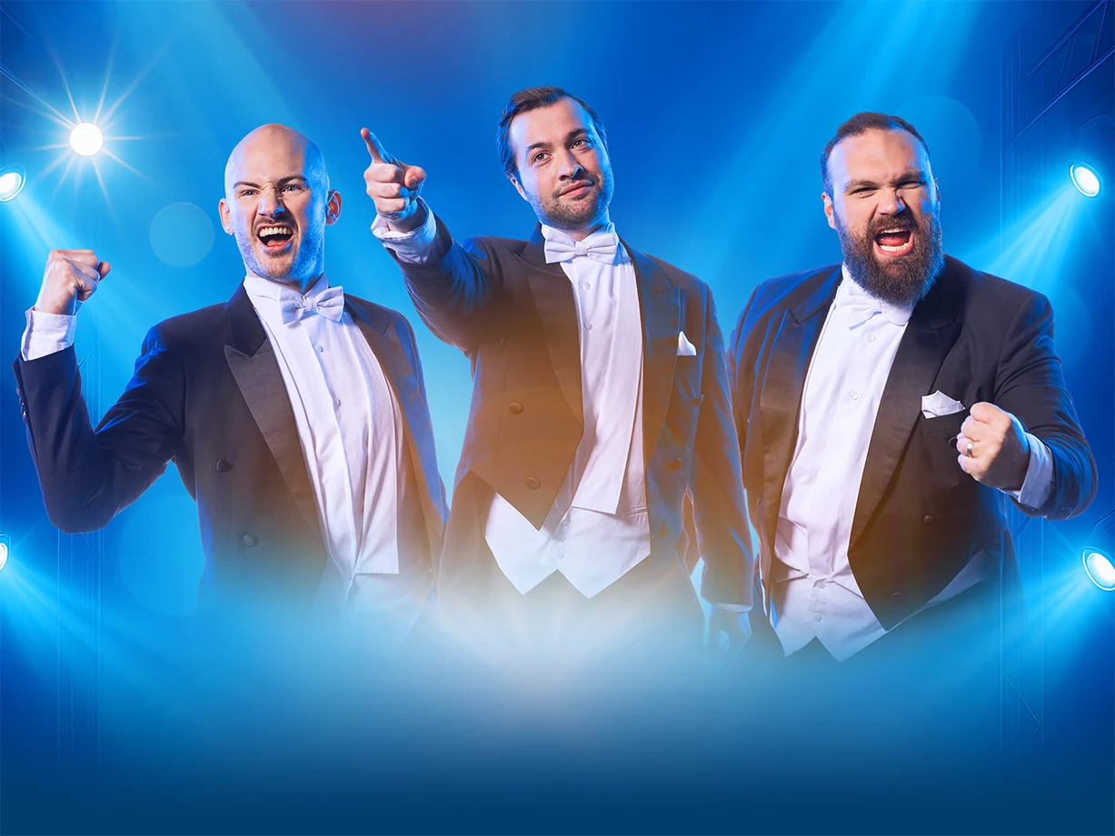 De drie Diamond Baritones in rokkostuum tegen een blauw decor.