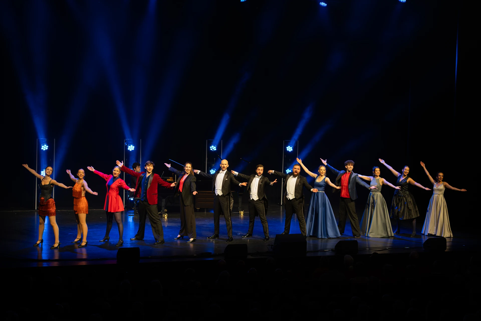 Het volledige ensemble van The Circle of Life onder blauwe podiumverlichting.