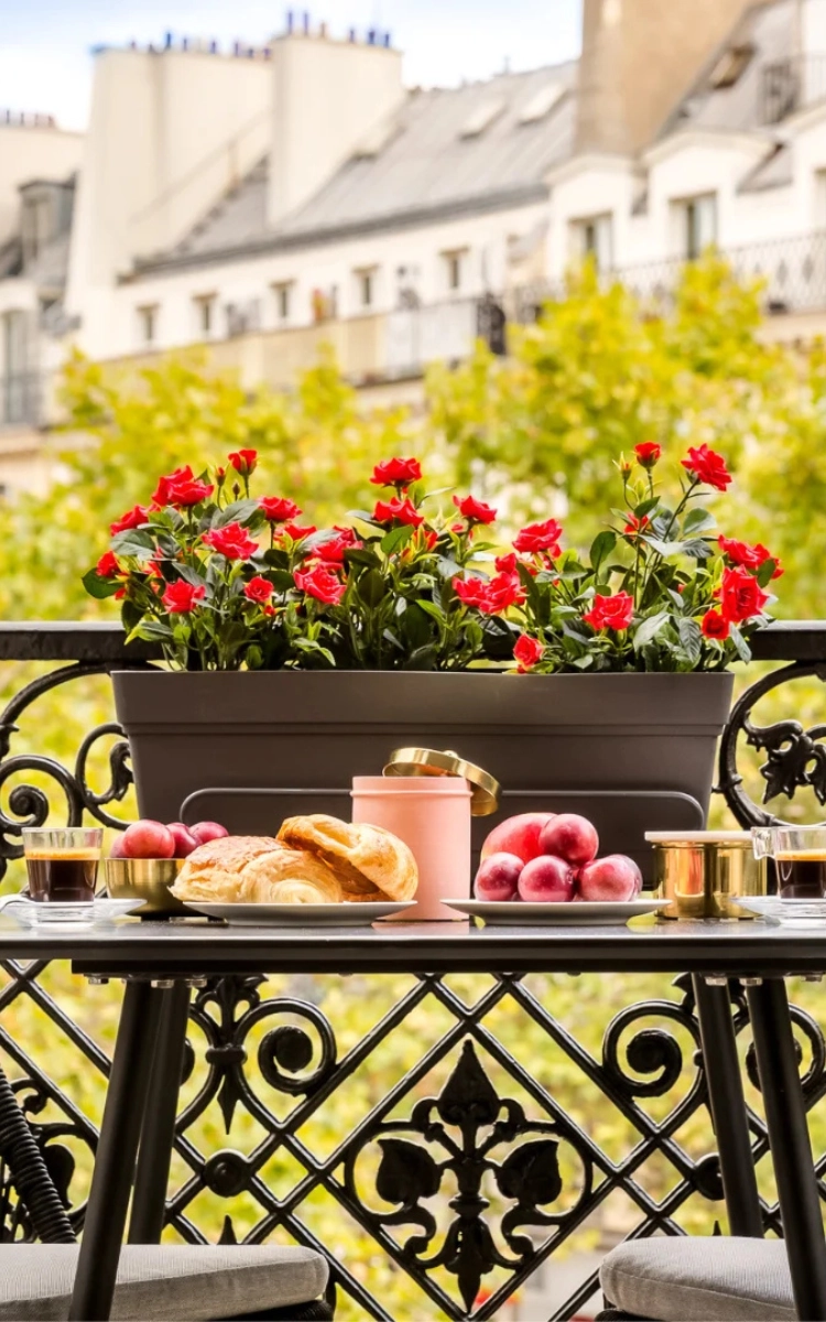 Balcon fleuri avec une table de petit-déjeuner dans un appartement de Merveil Paris