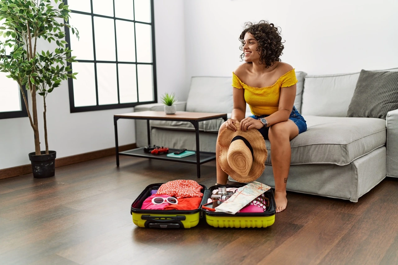 A woman sits near a packed luggage, preparing for a trip.