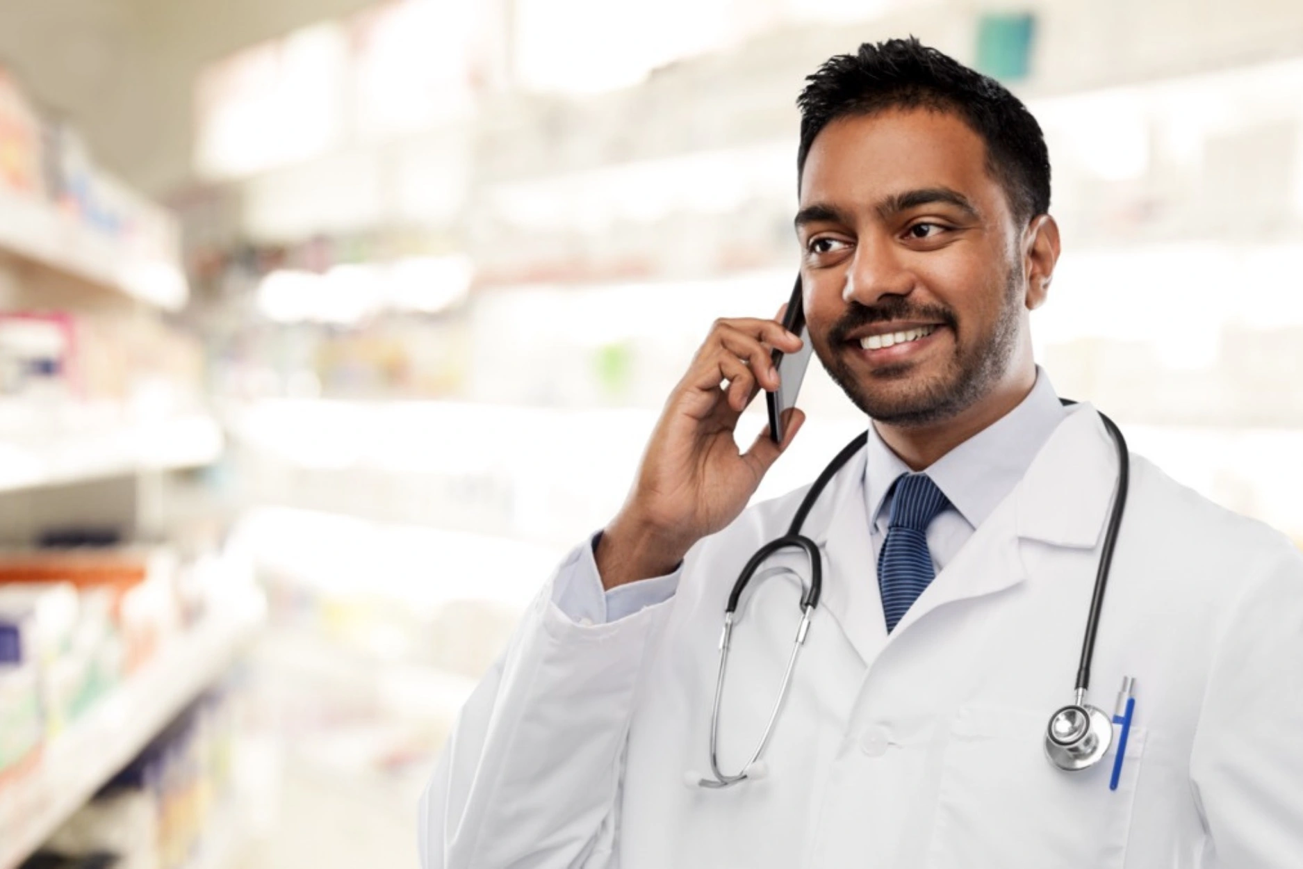 A doctor speaks on the phone at a pharmacy.