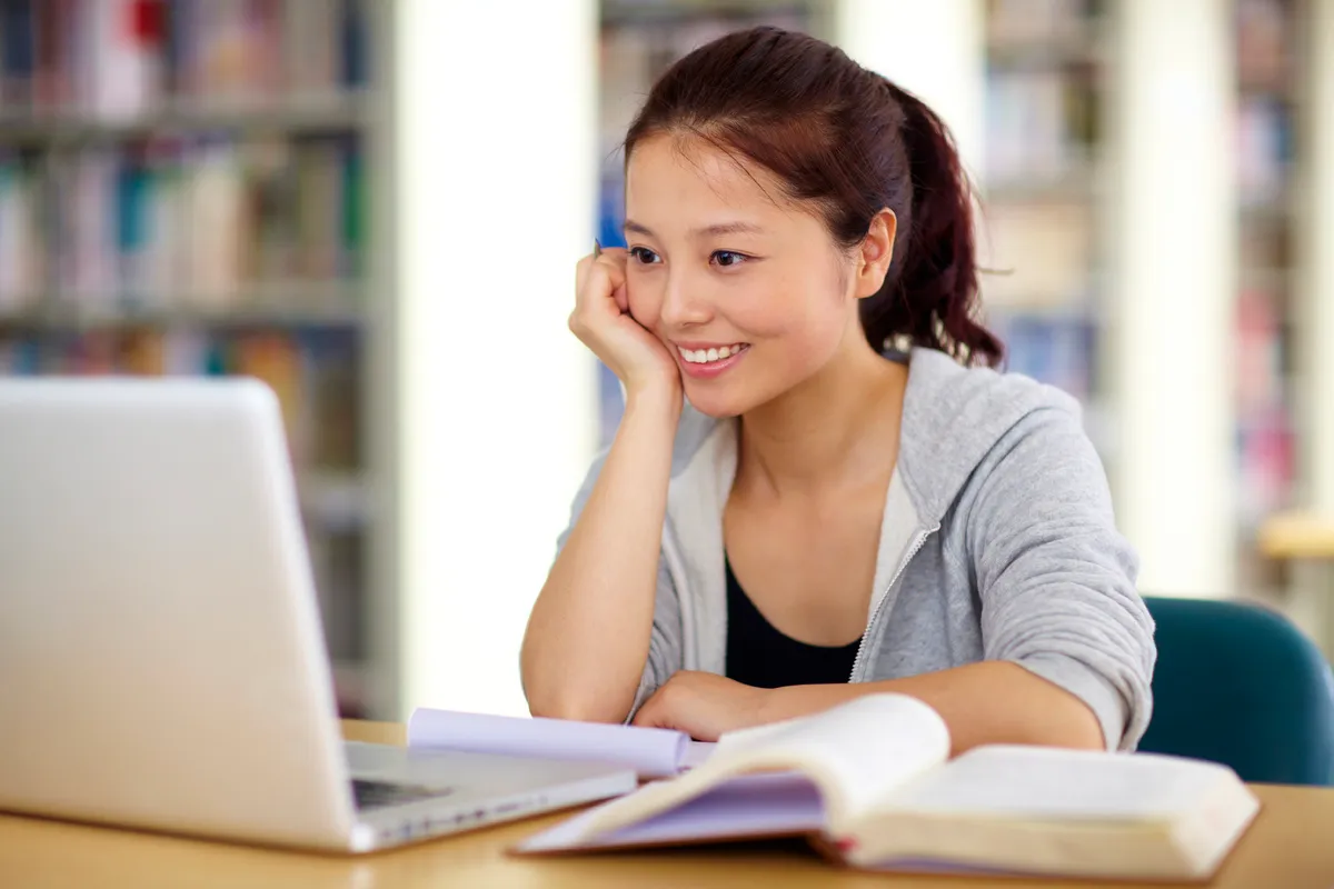A female student studying on her laptop in a library.