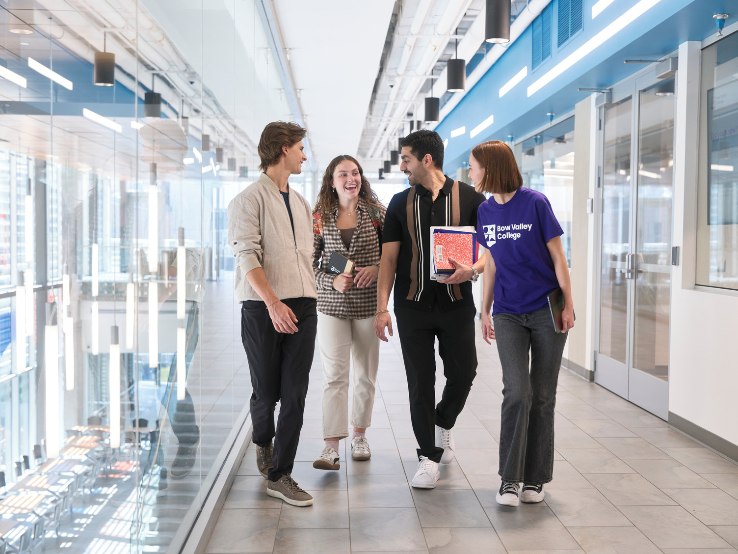 Four students walking and talking with each other at Bow Valley College's south campus hallway.