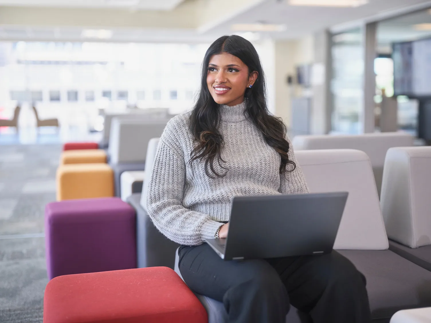 A female student working on her laptop in one of the lounge areas at Bow Valley College.