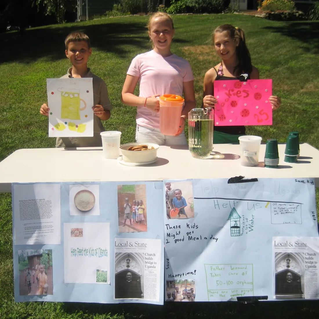 Three children at a lemonade stand with handmade signs and a poster board