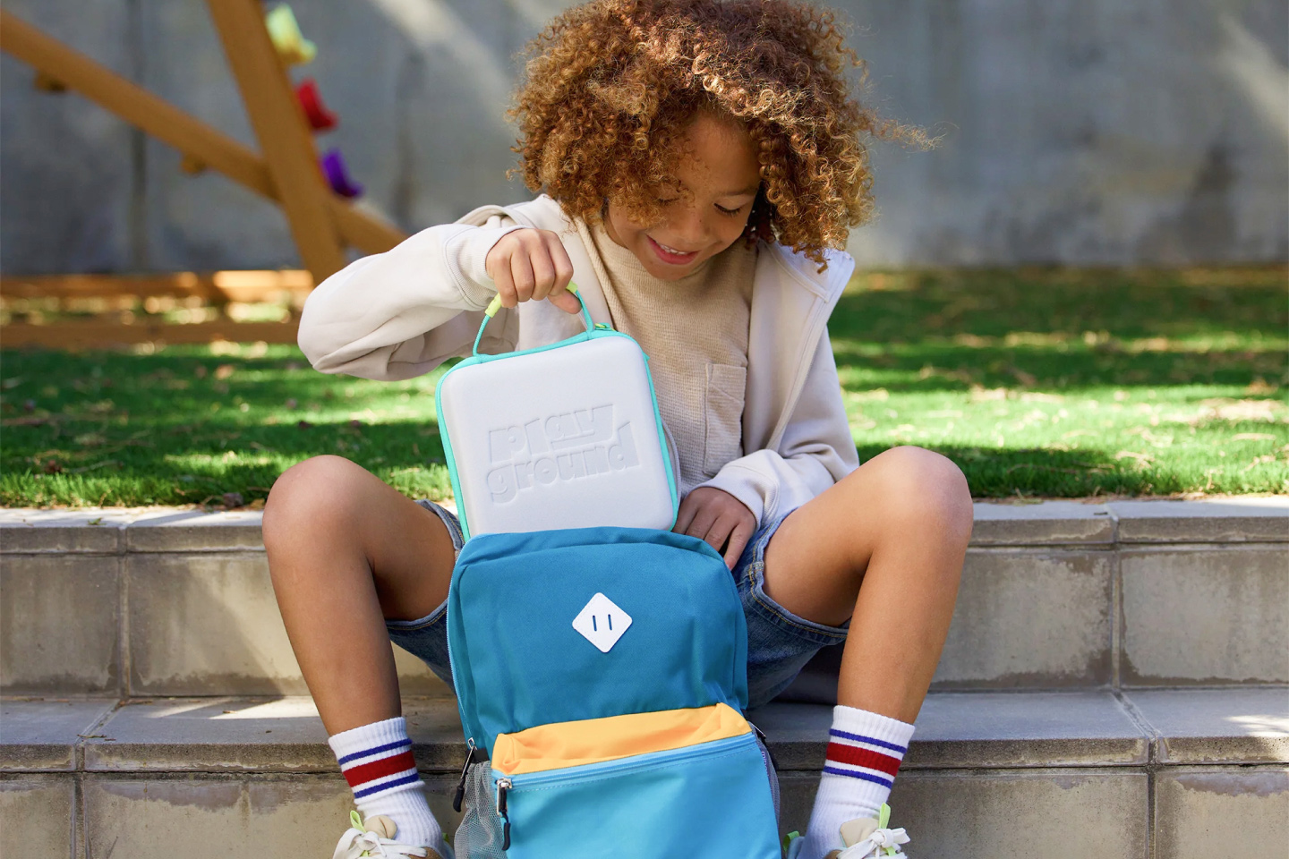 Kid putting a Nex Playground travel case into a backpack.