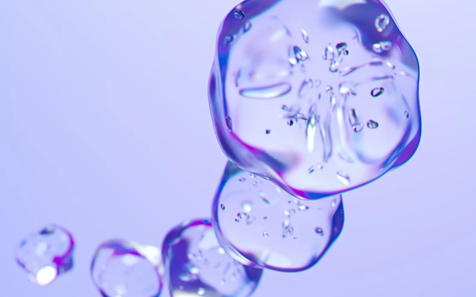 Close-up of translucent ice cubes with visible bubbles against a soft purple background.