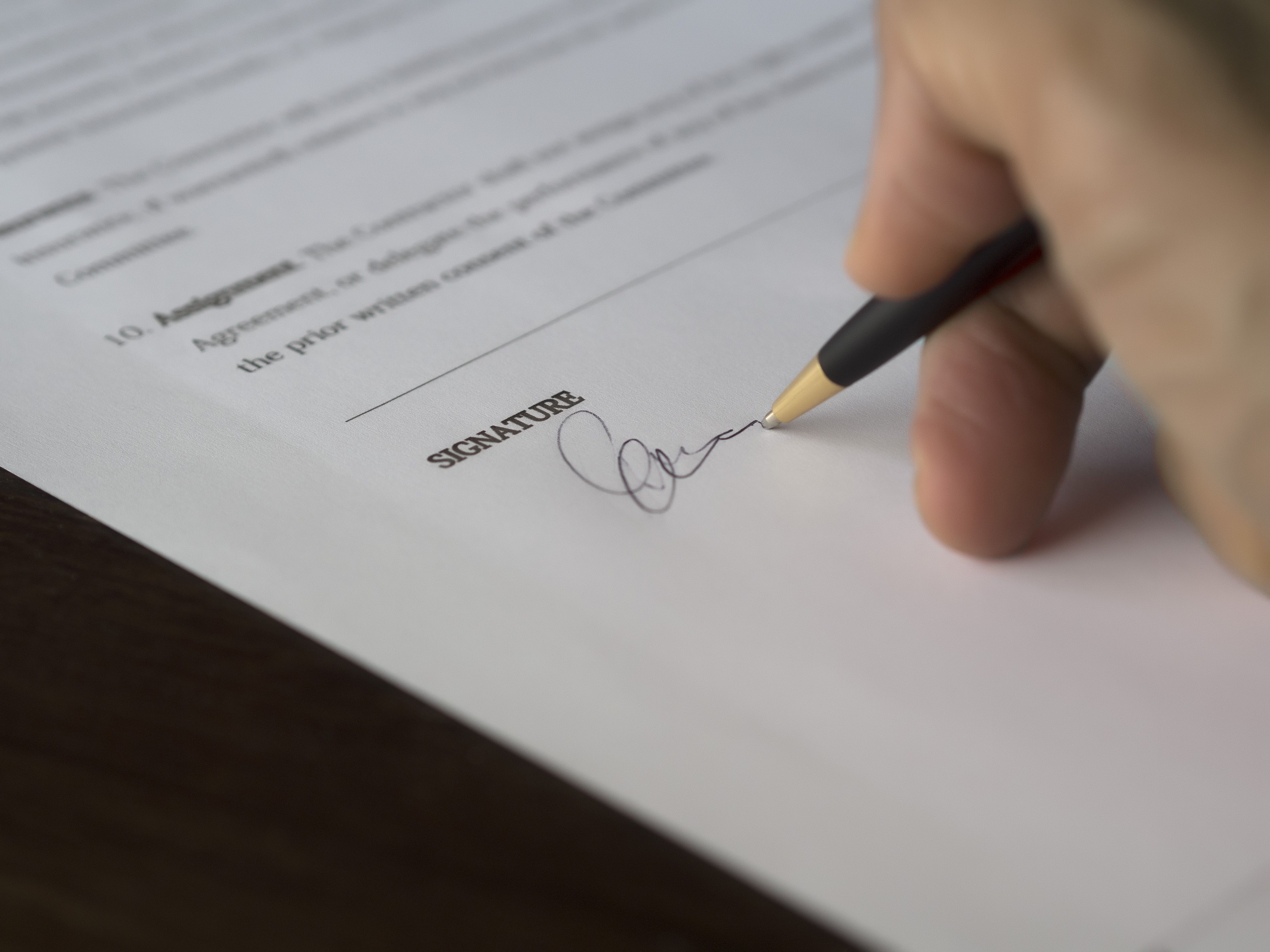A hand signing a contract with a pen