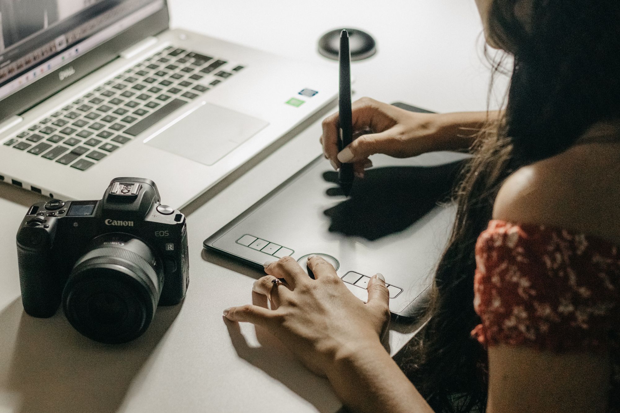 A designer working on a graphics tablet beside a laptop