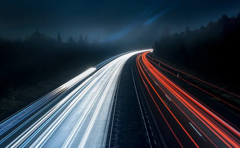 Light trails streaking along a night motorway, white on one carriageway and red on the other