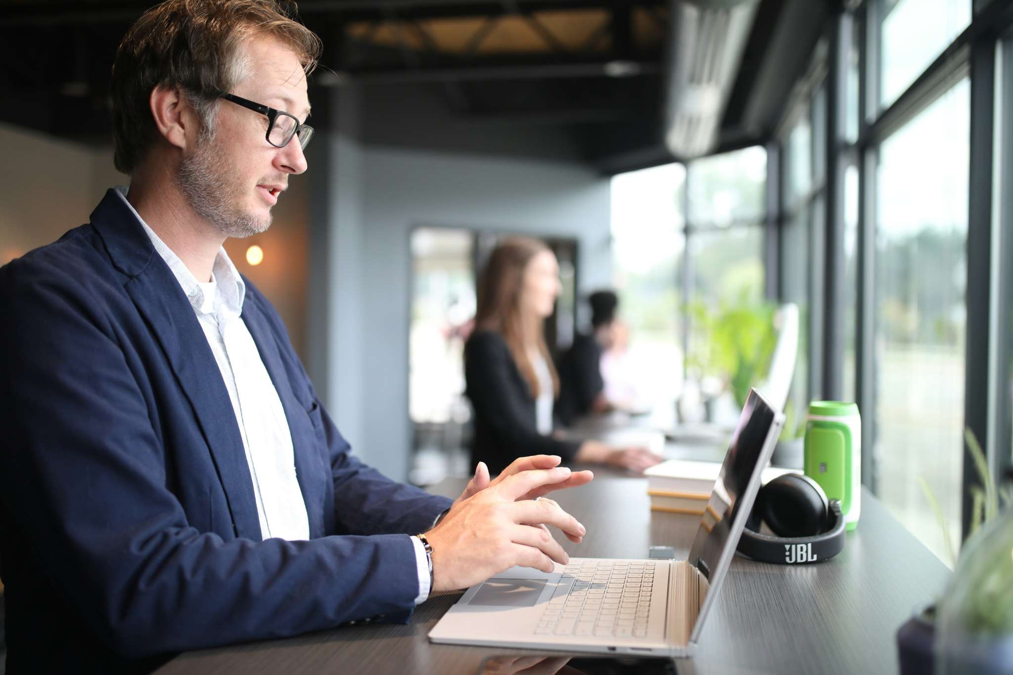 Un professionnel travaille concentré sur son ordinateur portable dans un espace de coworking moderne.