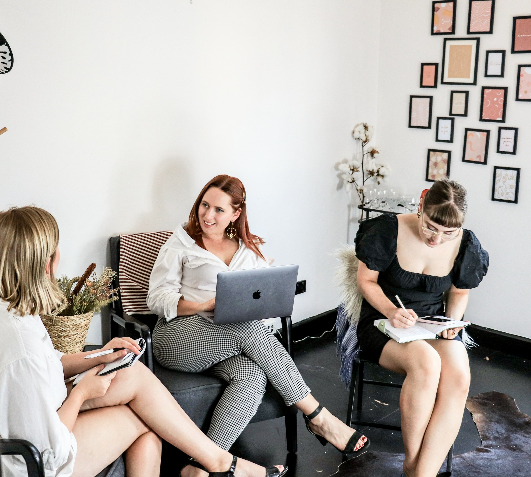 Trois collaboratrices tiennent une réunion informelle avec des ordinateurs et des carnets.