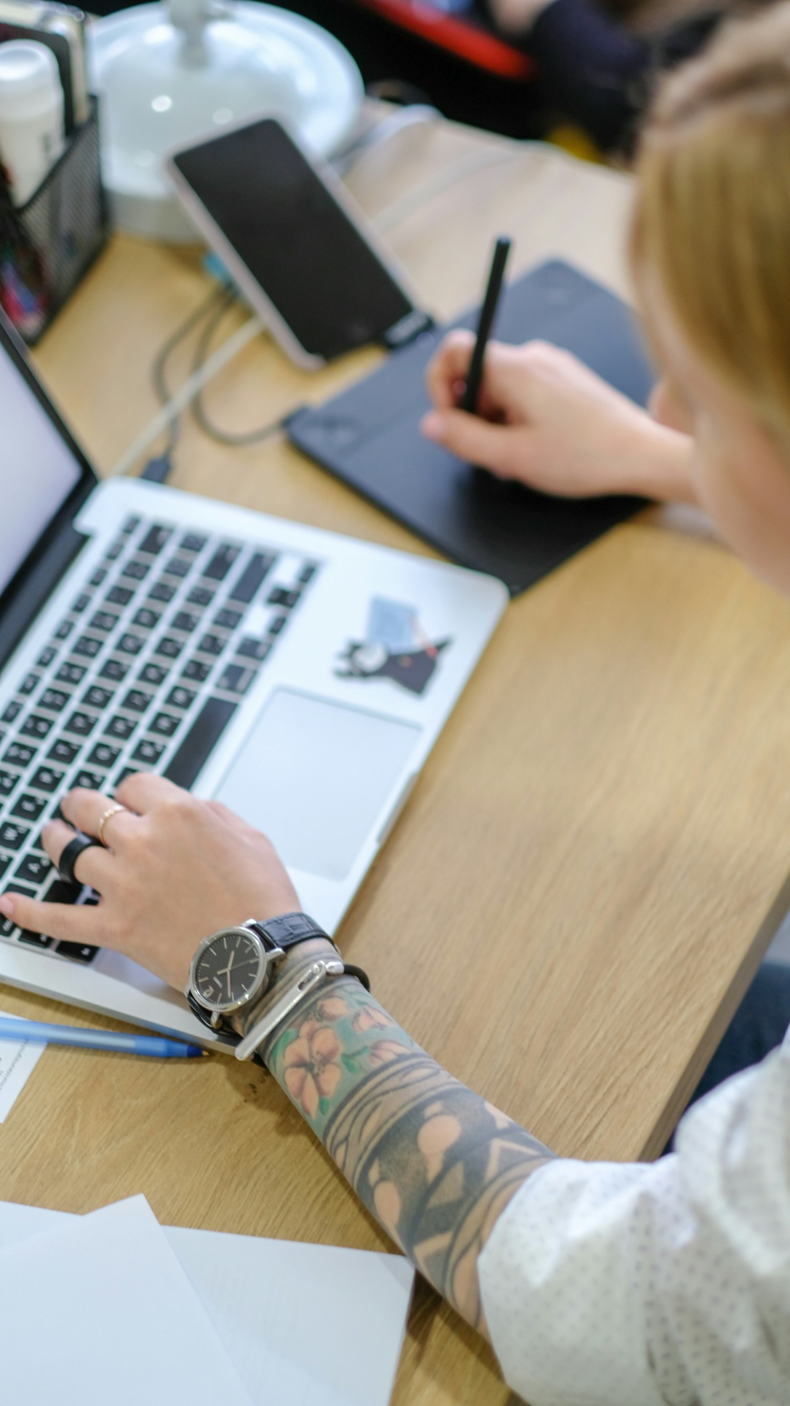 Une personne travaille sur un ordinateur portable et une tablette graphique dans un environnement de bureau.