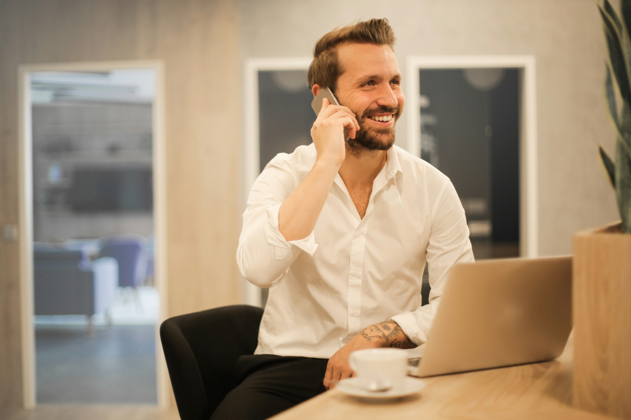 Un commercial échange au téléphone avec un client depuis son bureau.