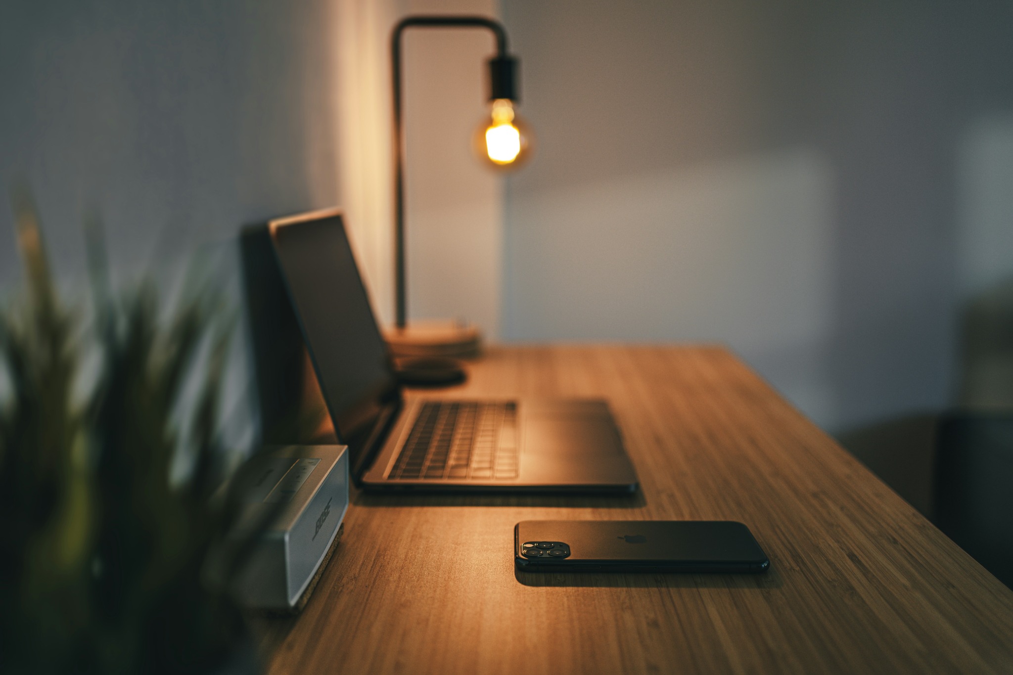 Un bureau moderne avec ordinateur portable, smartphone et lampe allumée, ambiance de travail calme.