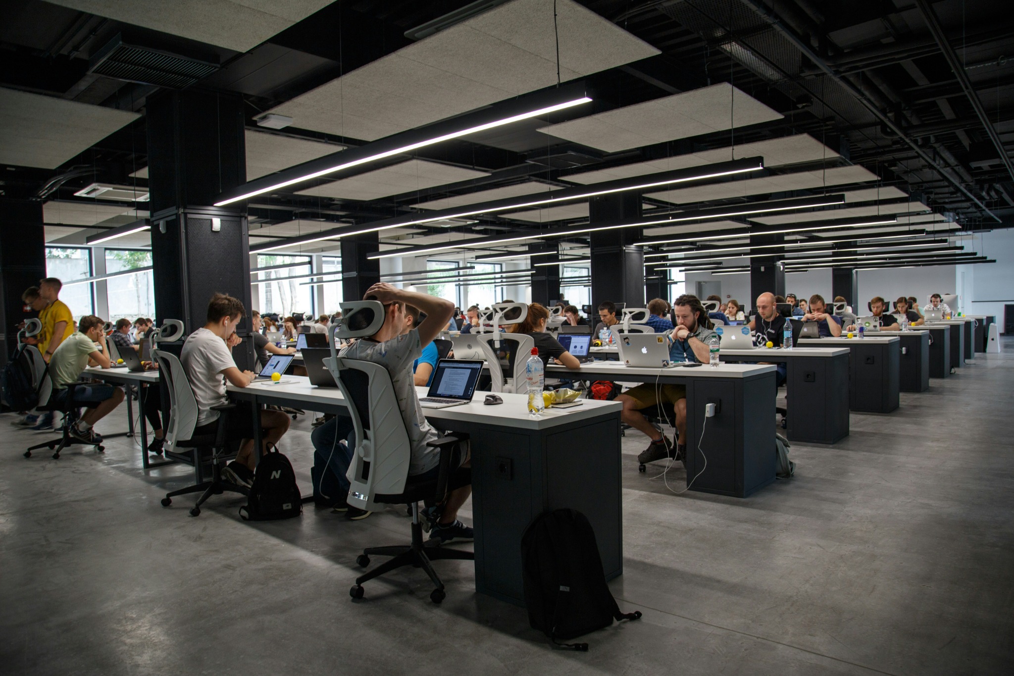 Un open space moderne où de nombreux collaborateurs travaillent sur leurs ordinateurs.