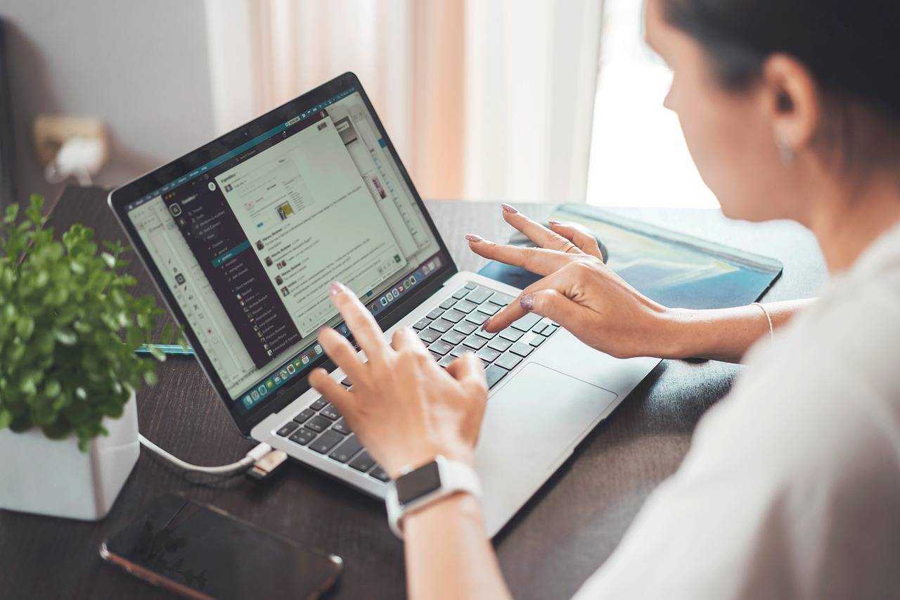 Une personne interagit sur Slack depuis son ordinateur portable, concentrée sur son écran.