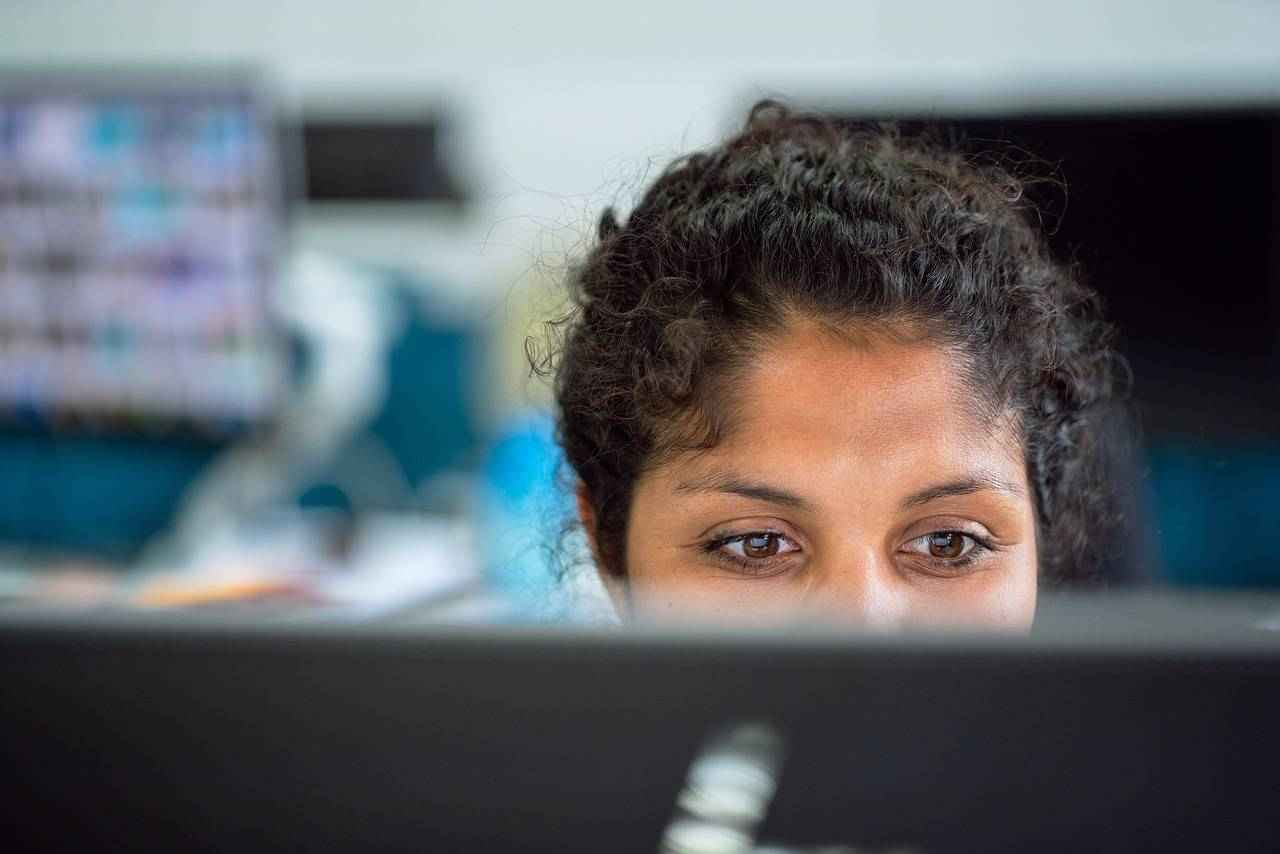 Un gros plan sur une employée concentrée derrière son écran d’ordinateur.