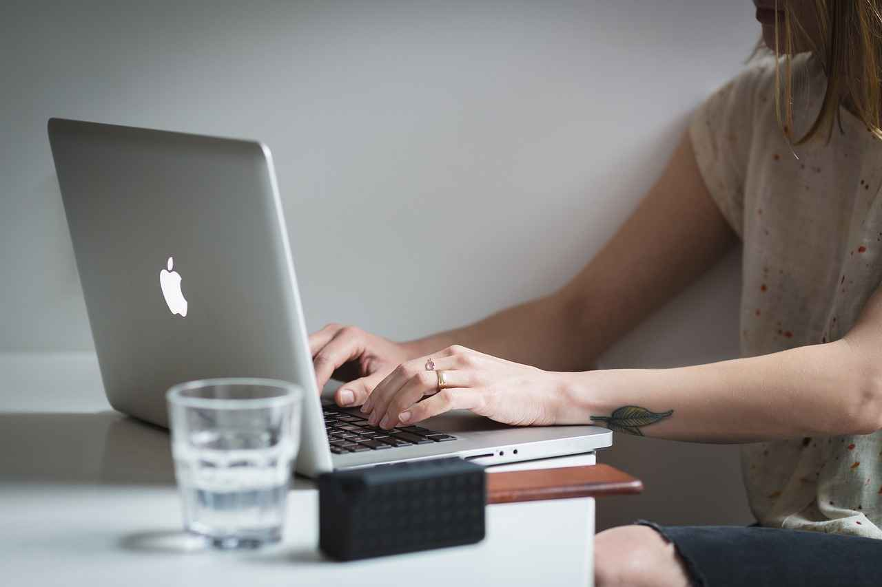 Une personne saisit du texte sur un ordinateur portable, concentrée dans un environnement calme.