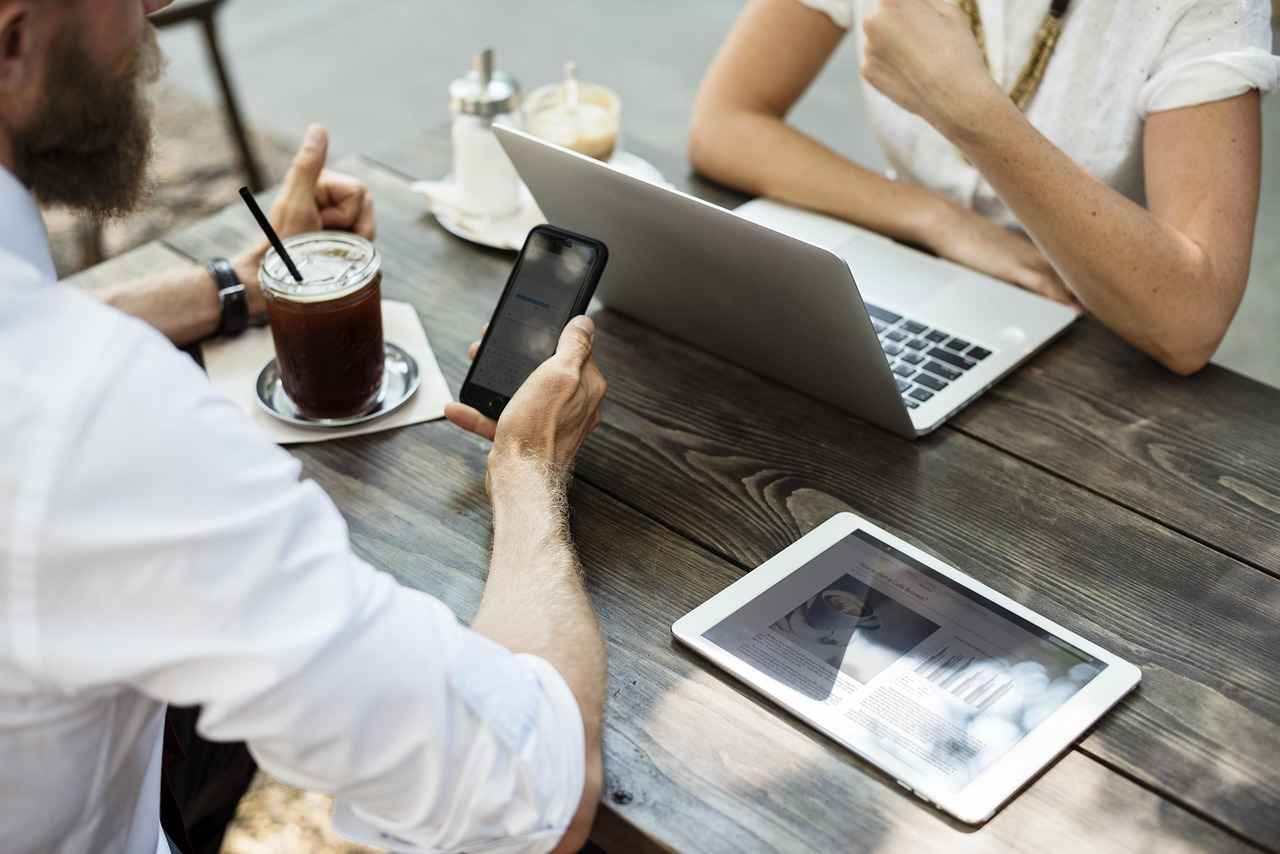 Entretien informel entre deux professionnels travaillant sur ordinateur et tablette.