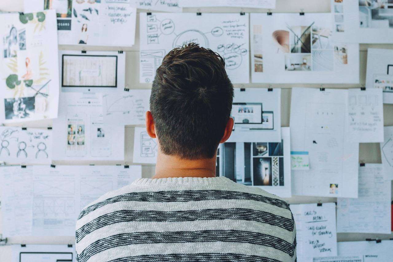 Un collaborateur analysant un mur de documents et de schémas stratégiques.