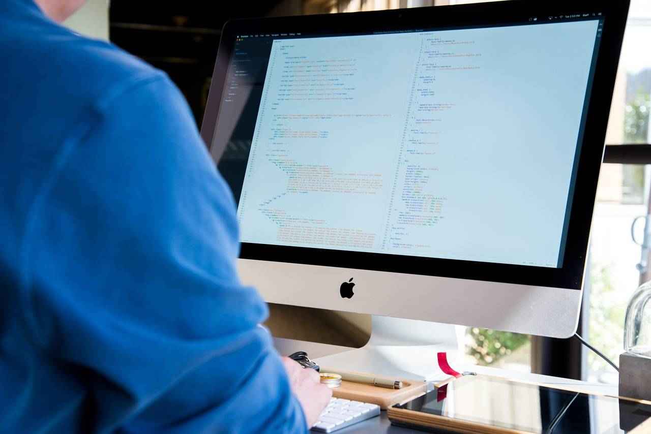 Un professionnel travaille sur un écran d’ordinateur affichant du code, illustrant le développement ou l’ingénierie informatique.