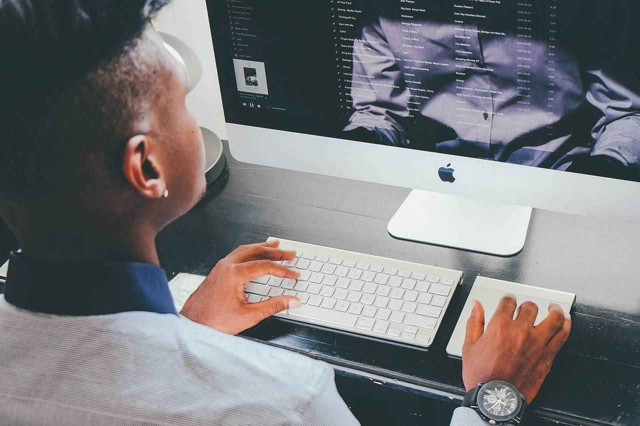 Un professionnel analyse du contenu commercial sur ordinateur, illustrant la préparation stratégique avant une communication LinkedIn.