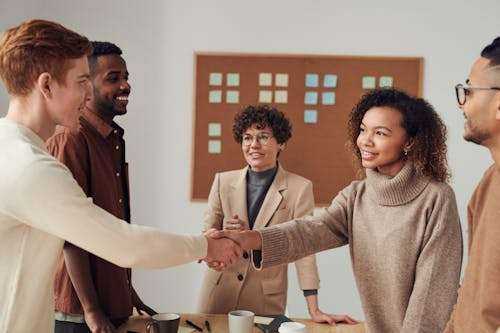Collaboration et échange de poignée de main entre plusieurs collègues dans une ambiance de travail dynamique.