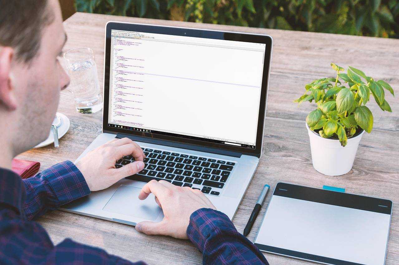 Développeur travaillant sur un code informatique dans un environnement de travail extérieur.
