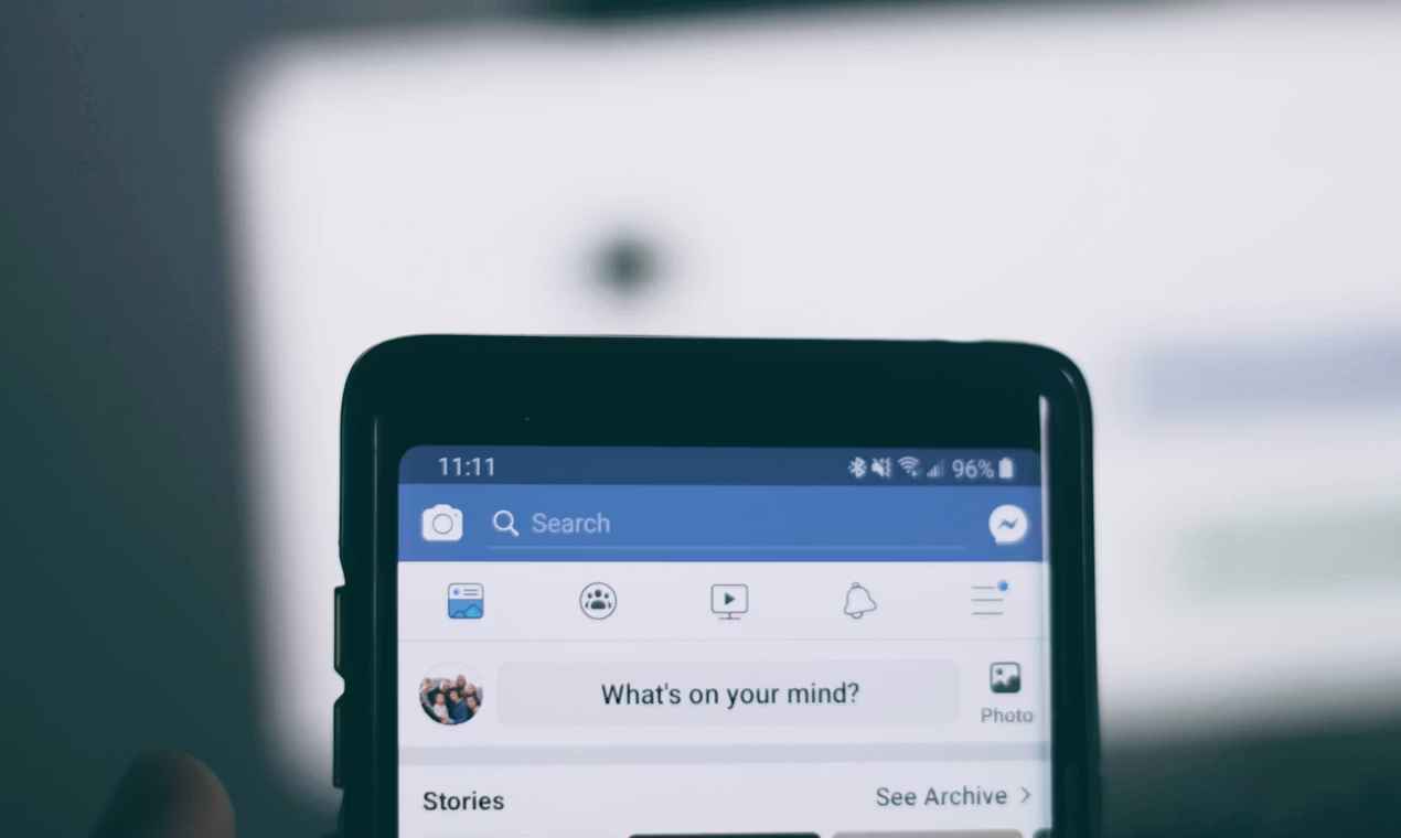 Interface de Facebook affichée sur un téléphone, montrant le fil d'actualités et l'option pour publier un statut.