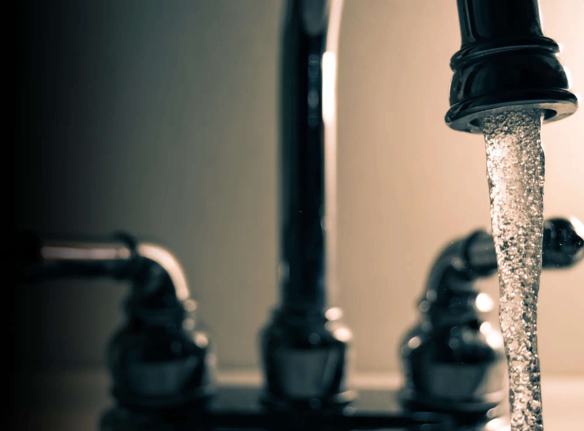 A black and silver faucet with water dripping from it.