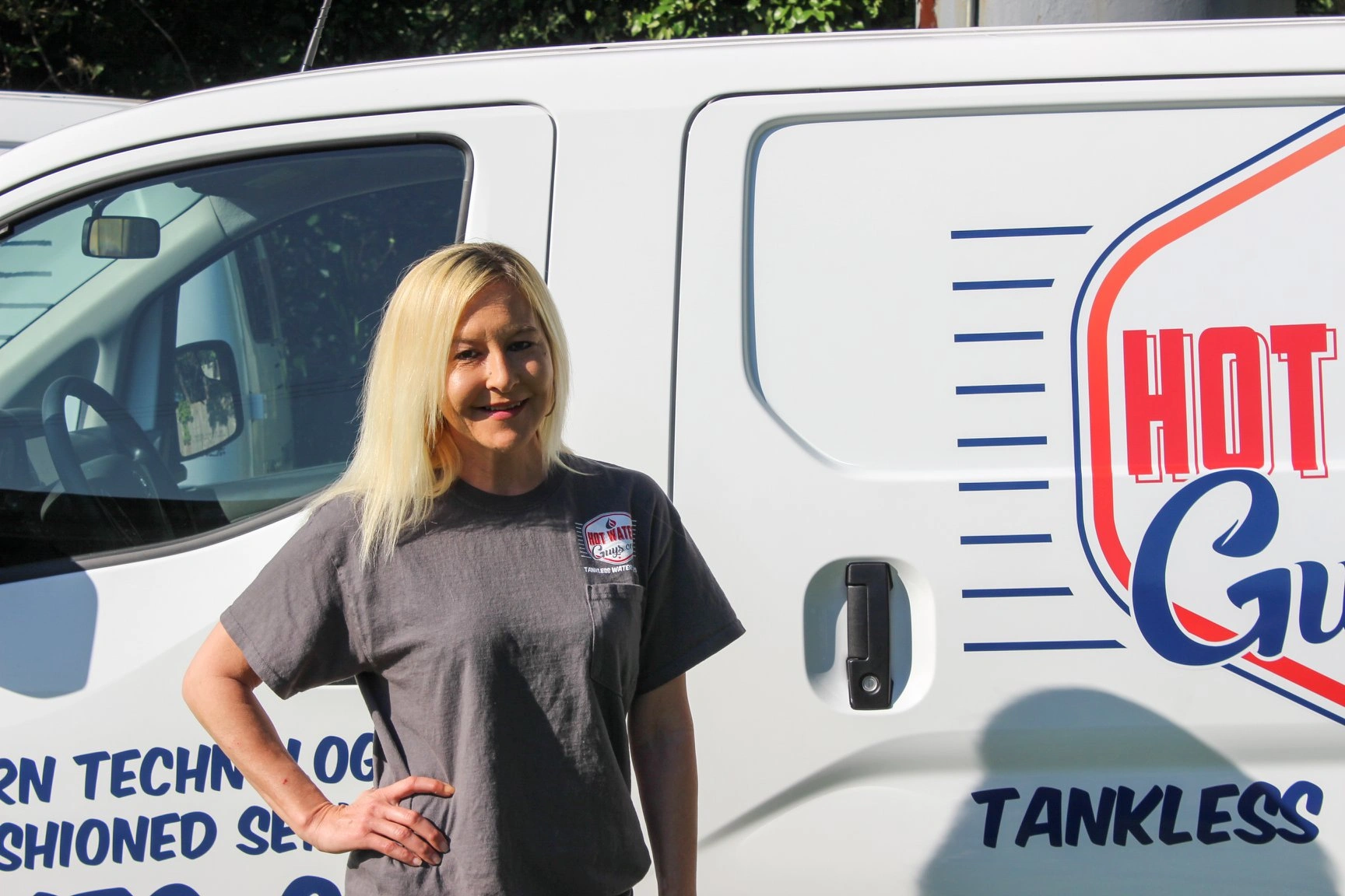 Hot Water Guys team member standing in front of one of their installation vans