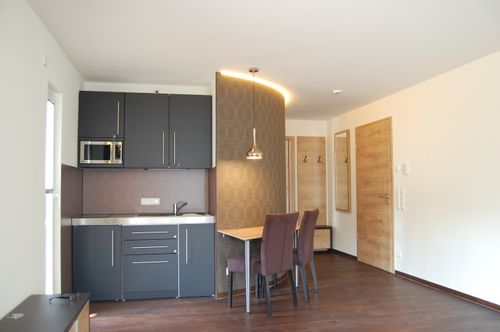 Gemütliches Hotelzimmer im Waldhotel Rainau mit moderner Küchenzeile, elegantem Essbereich und stilvoller Beleuchtung.