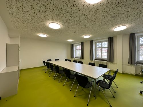 Renovierter Konferenzraum in Ellwangen mit moderner Akustikdecke, großzügigem Besprechungstisch und frischem grünen Bodenbelag.